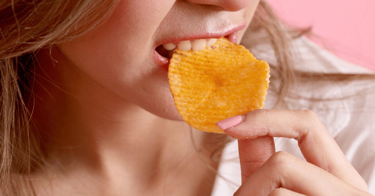 Close-up of a woman biting into a potato chip