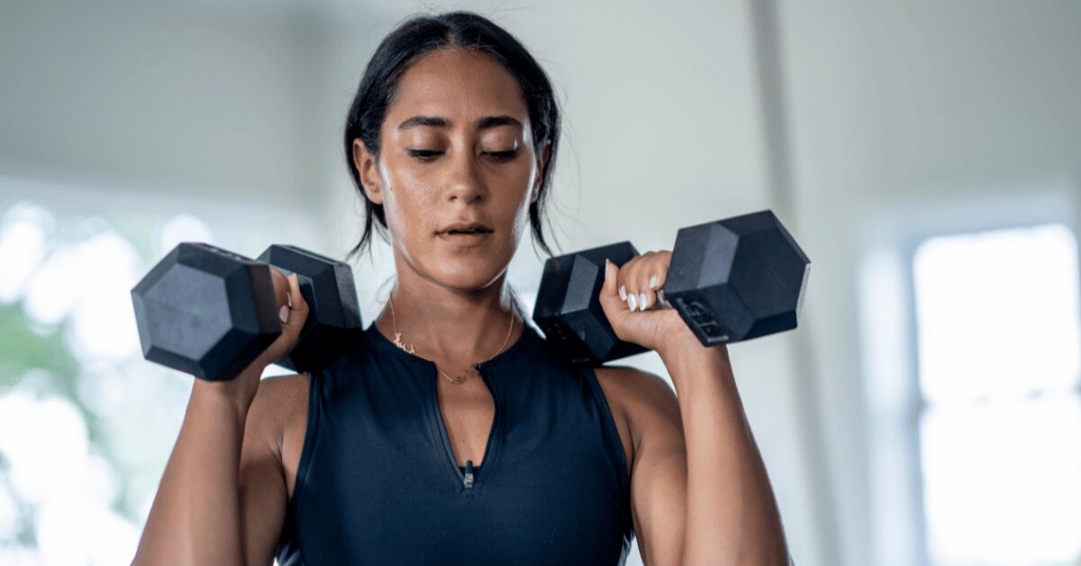 Woman doing a dumbbell shoulder press during a strength training workout