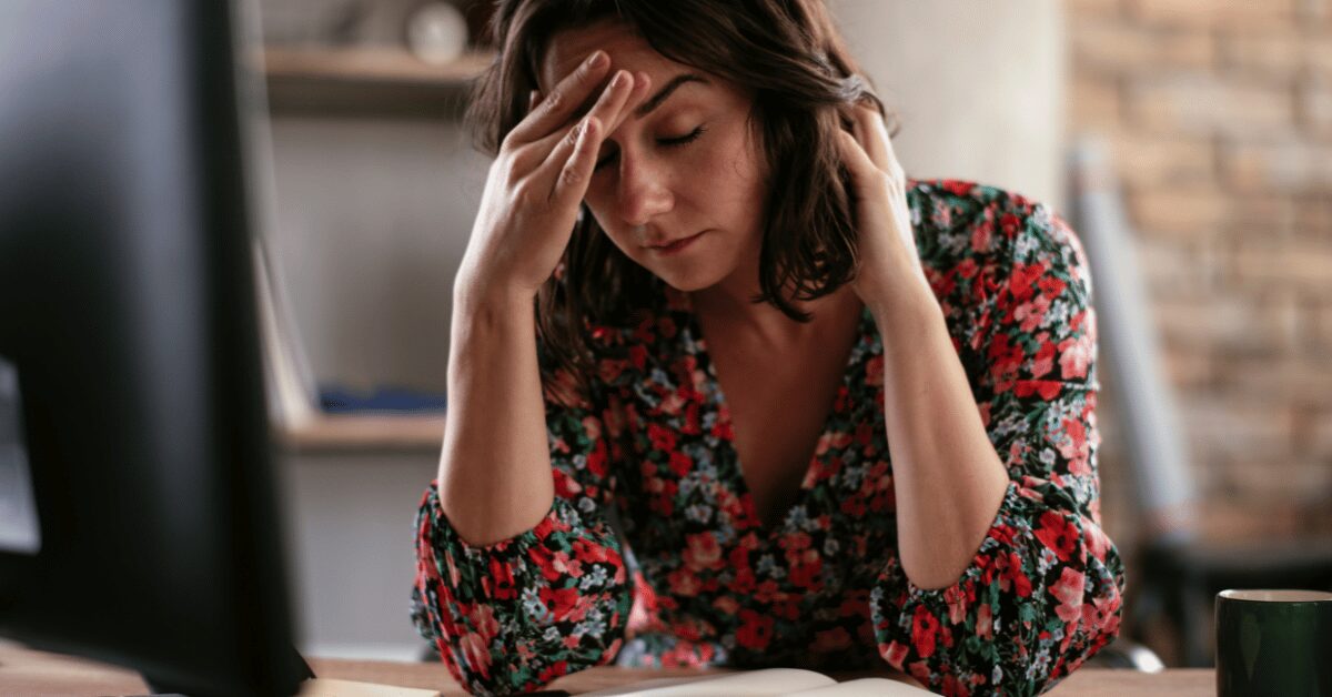 Woman in her 30s sitting on her bed in the morning, looking tired