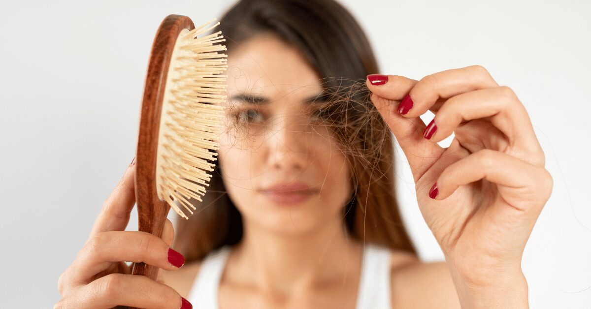 Woman holding a hairbrush and a strand of shed hair